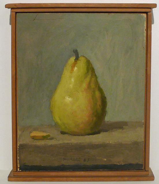Green pear with almond on brown table in wood frame