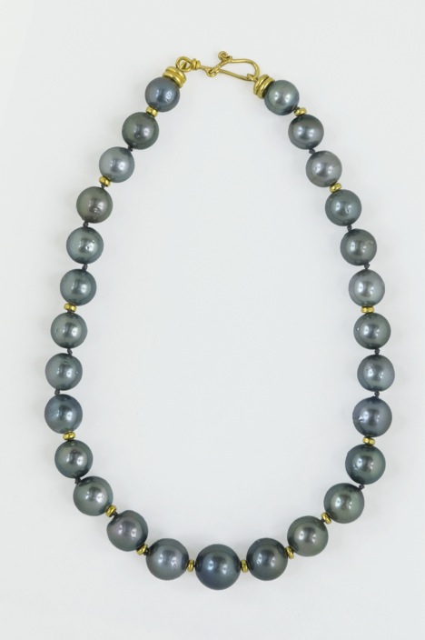 Large dark grey pearl necklace laid flat on white surface