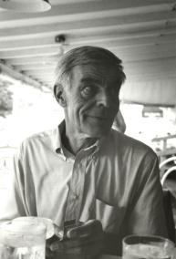 Albert York wearing collared shirt at center looking to the right of photograph with hands and water glasses on table