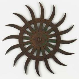 Rust plow wheel with spikes on white ground