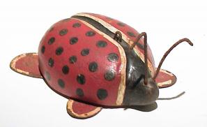 Wooden ladybug painted red with black dots and black stripe facing right