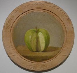 Green apple with slice removed on table pn wooden circular plate