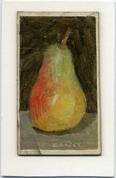 Green and red pear on grey table in front of black wall
