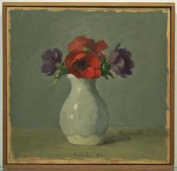 Red and purple flowers in white vase on grey table in front of grey wall in wood frame