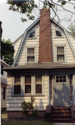 White house with blue trip, brick chimney and stairs