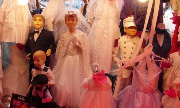 Dolls in bridal dress, tuxedo and soldier outfits surrounded by white and pink tulle dresses