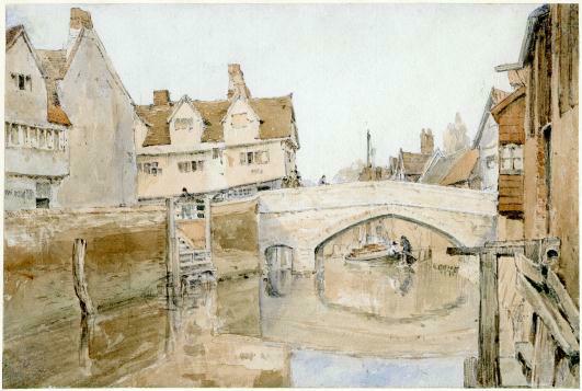 Bridge with boat beneath and riber with houses on either side of riverbanks