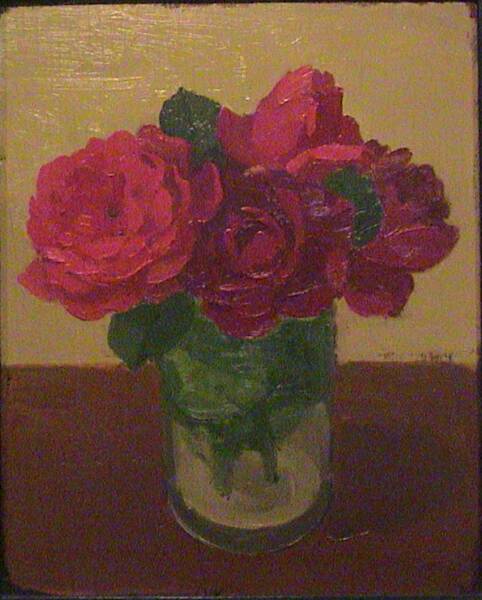 Red roses and green leaves in a glass jar on brown table in front of ochre wall