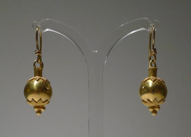 Gold bead earrings with granulation at top and bottom of beads suspemded from clear earring tree