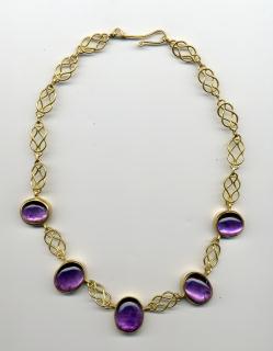 Gold knotted necklace with five purple bead necklace, clasped and laid flat on white surface