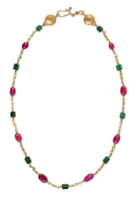 Clasped gold necklace with pink and emerald beads laid flat on white surface