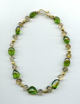 Green, clear, and gold bead necklace clasped, and laid flat 