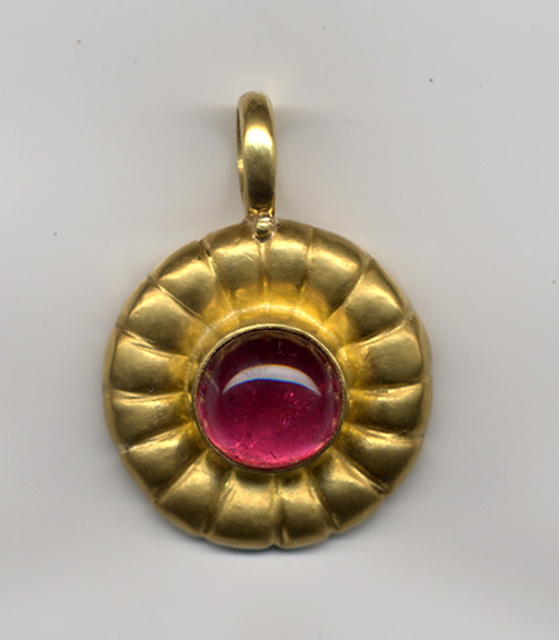 Gold pendant with with magenta gem on white ground