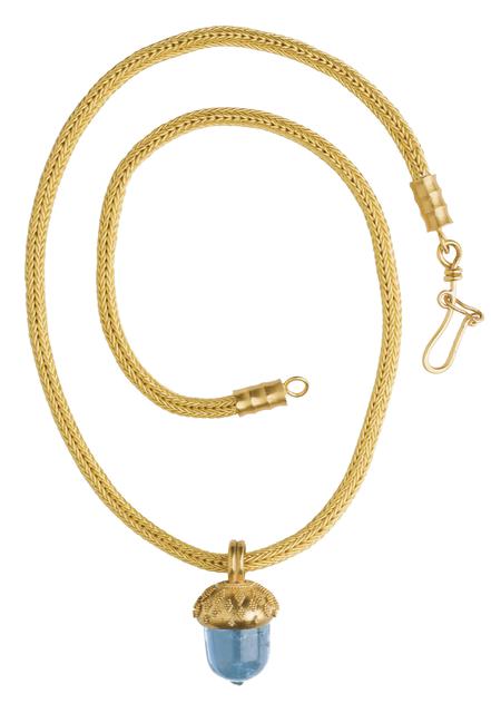 Gold chain necklace with blue acorn bead laid in a sprial flat on white ground