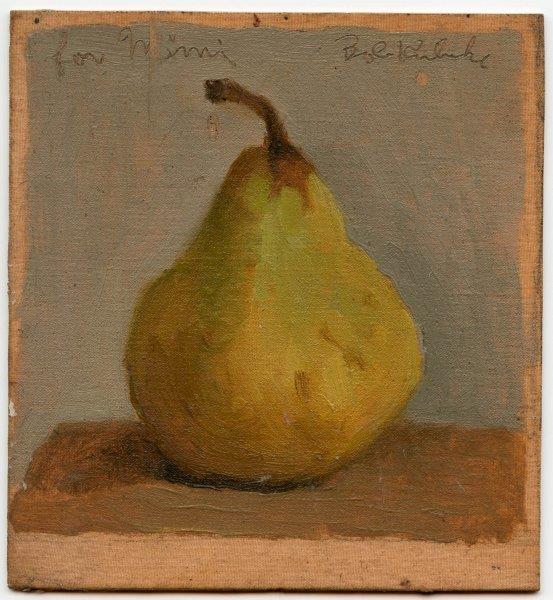 Green pear with stem on brown table in front of grey wall