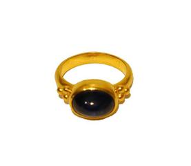 Sapphire in gold ring with clustered granulation on either side laid flat on white ground