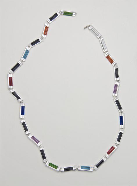 Silver necklace with sequence of differntly colored cylindrical tubes laid flat on white surface
