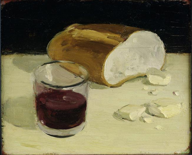 Cut loaf of bread, pieces of butter, and half filled cup of red wine on yellow table in front of black wall