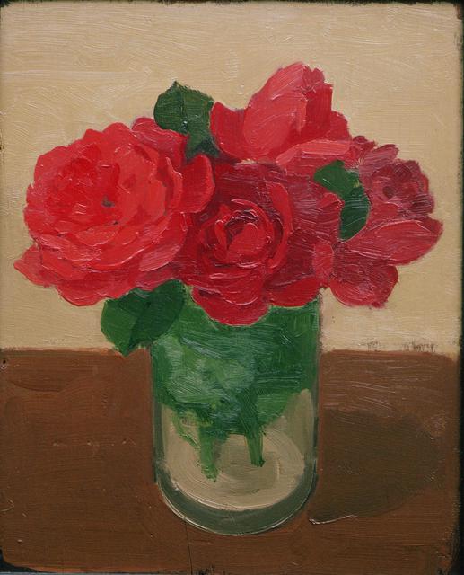 Large red roses with green leaes in glass jar on brown table