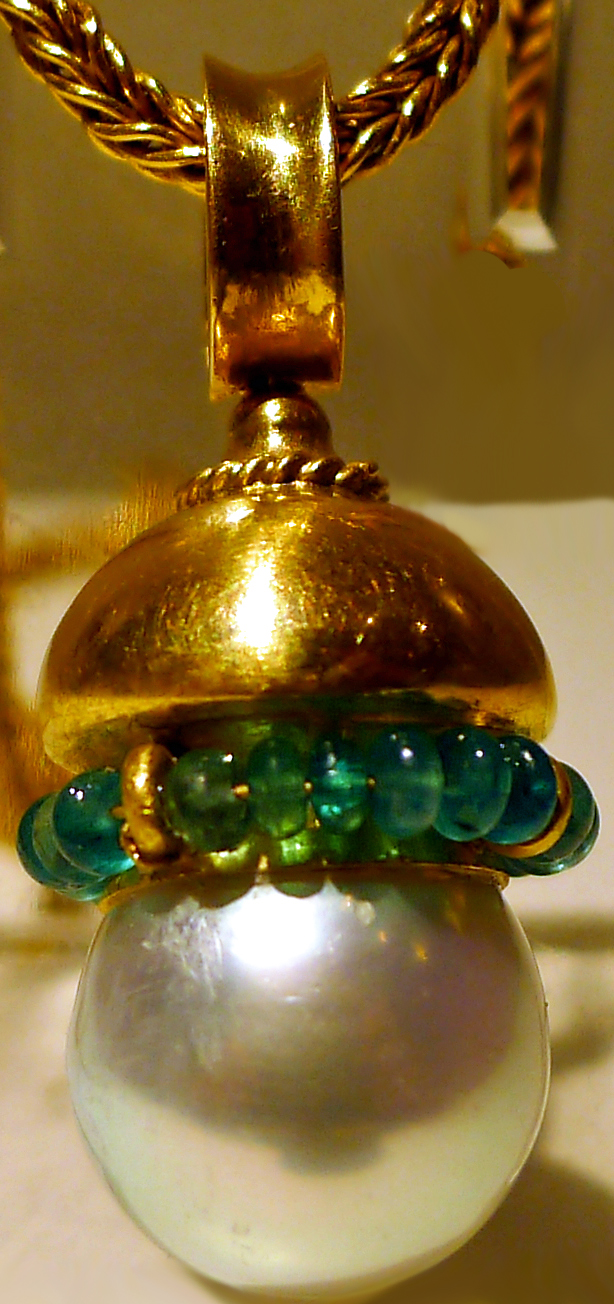 Gold pendant with emerald beads above pearl