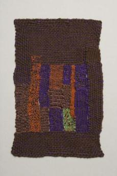 Brown rectangular weaving with square off-center towards lower left of orange, purple and brown stripes with one green stripe