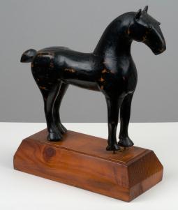 Black wooden horse on rectangular stand on white table