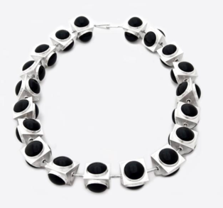 Black circles on silver three dimensional triagnles form necklace on white background