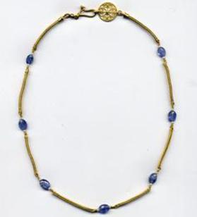 Blue beads with gold chain segment necklace, clasped and laid flat on white ground